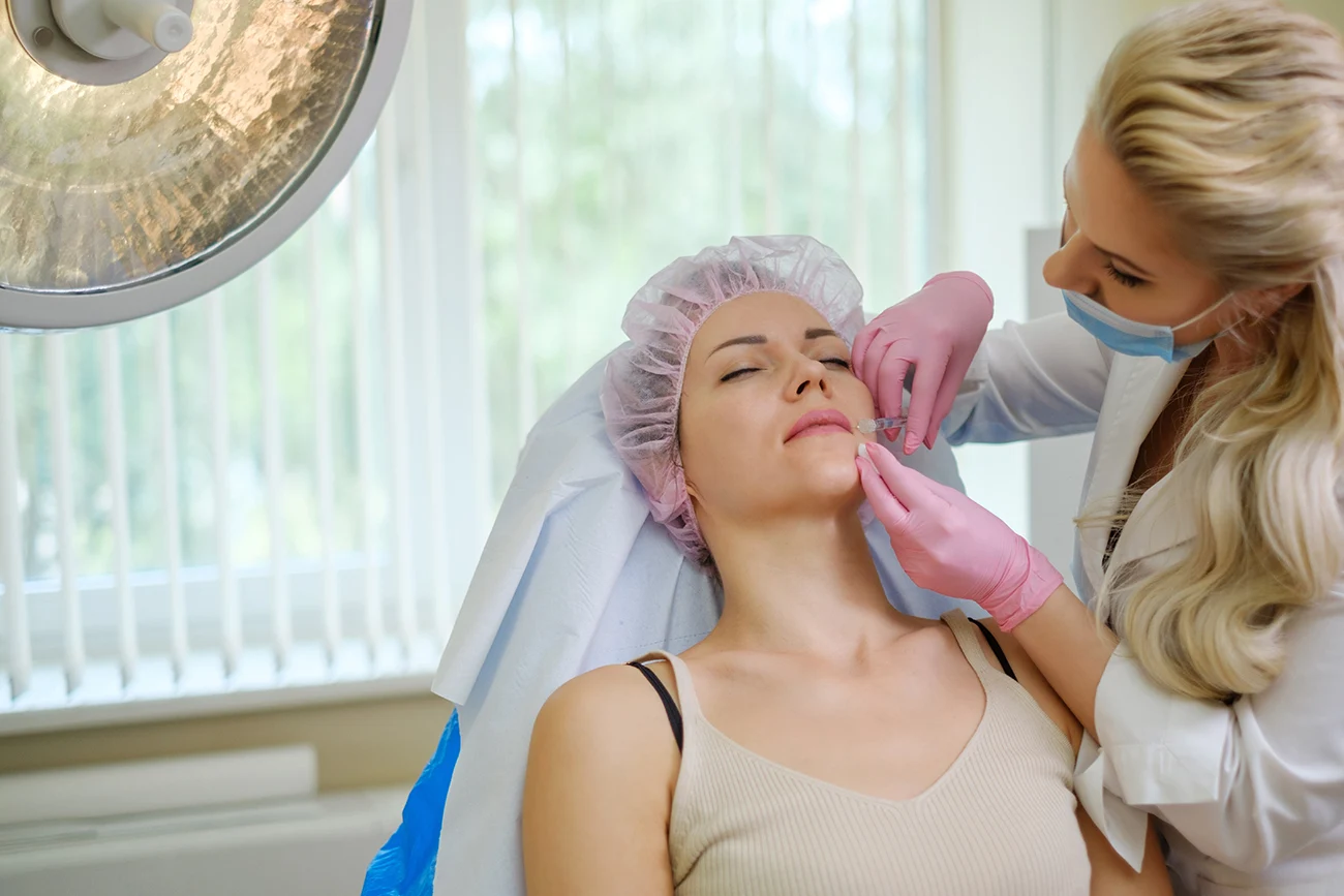 Female practitioner performing cosmetic facial injections on a patient in a medical spa or aesthetic clinic.